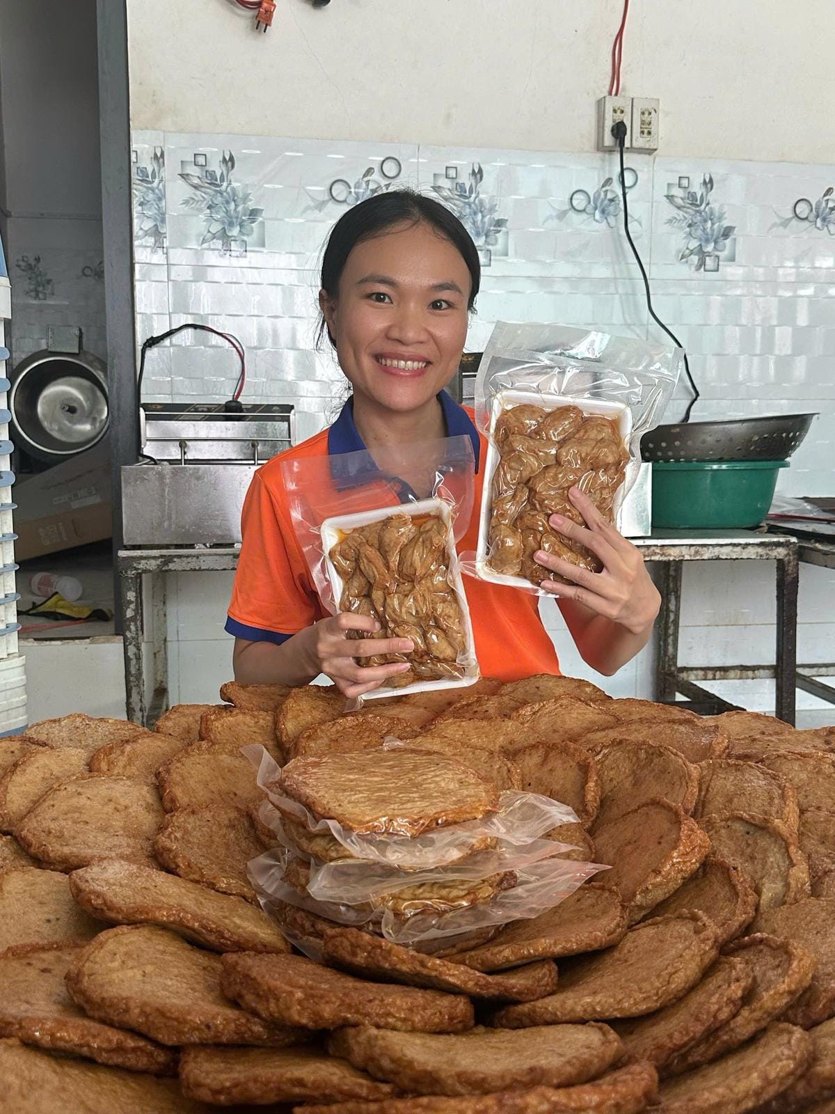 Xóm Biển Gửi 200kg Chả Cá Chiên Về Bình Dương Cho Khách Đi Mỹ 1 Chị Uyên ôm chồng chả cá chiên bánh tròn vàng ruộm vừa ra lò tại xưởng Xóm Biển Nha Trang
