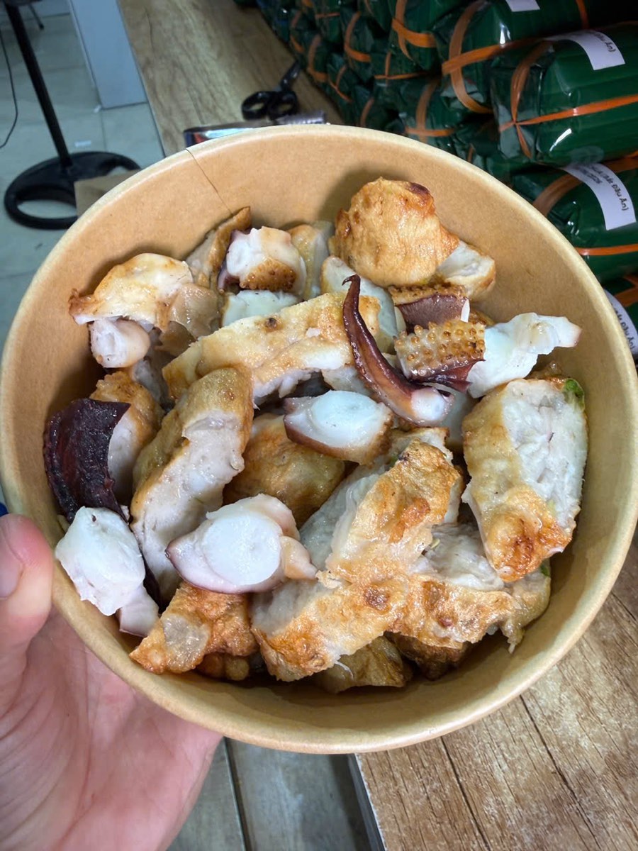 Chả Cá Nha Trang Giá Bao Nhiêu 1kg? Bảng Giá Mới Nhất 2026 4 Chả mực chiên quay nóng cắt sẵn trong tô giấy tại cửa hàng Xóm Biển