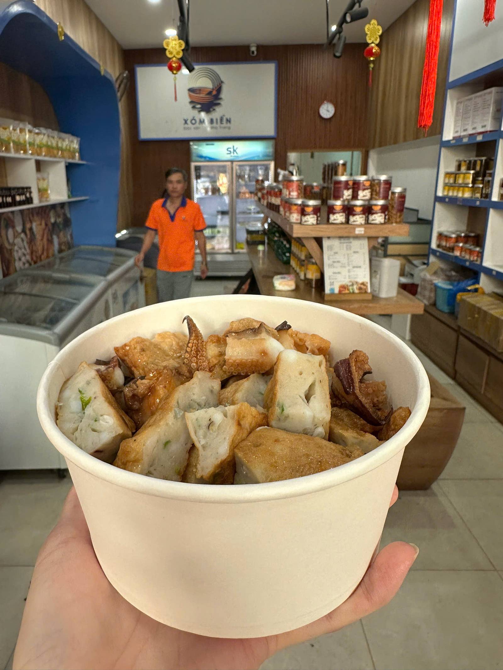 Chả Mực Nha Trang Ăn Sao Cho Đúng Vị? Chọn Cay Hay Không Cay 1 Chả mực Nha Trang cắt miếng trong tô giấy tại quầy Xóm Biển